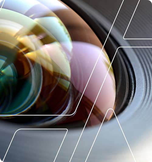 Close-up of a camera lens with colorful reflections and white geometric line overlays