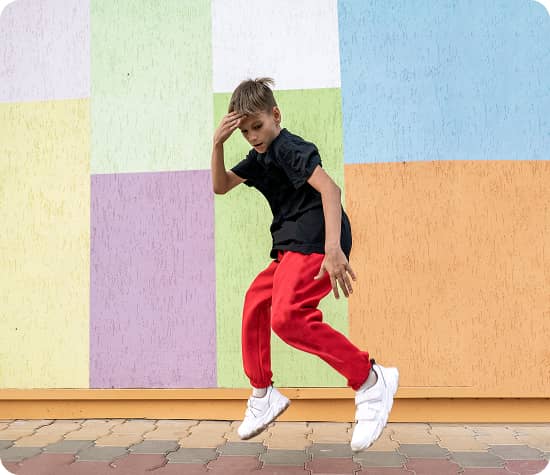 Child dancing in front of a colorful tile wall