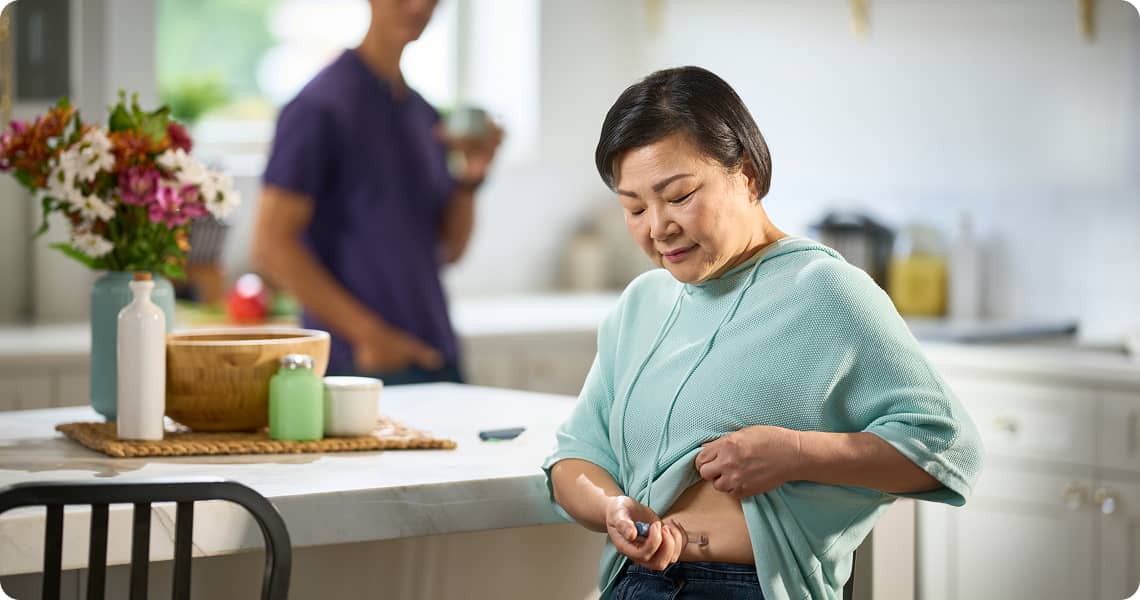 Person using an injection pen in their kitchen