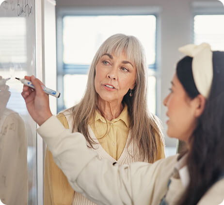 Two people writing on a whiteboard