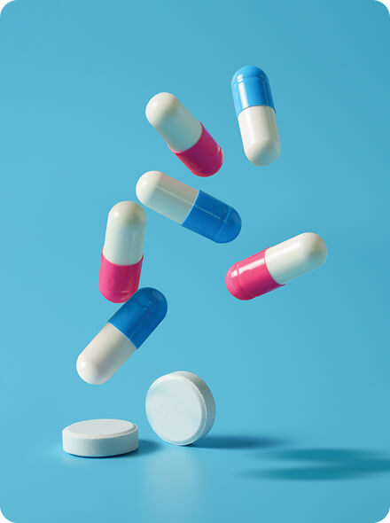 Pills and tablets falling on a light blue background